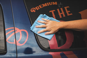 A person drying a car with a Standard Waffle Weave ight blue towel.