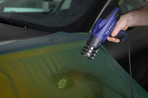 A person using the Weldy to heat vinyl over a car exterior.