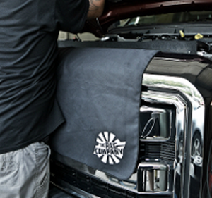 A person working on a car engine with a towel to wipe his hands on.