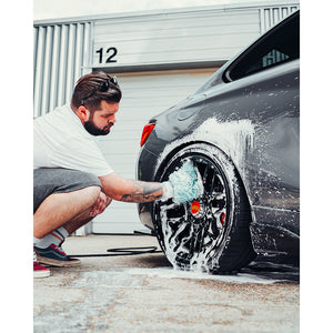 A person scrubbing a wheel rim with a TRC Ultra Mitt.