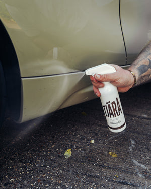 A person spraying the side of a car with Stjarnagloss.