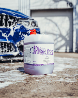 A jug of Stjarnagloss Matta in front of a foamy blue car.