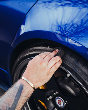 A person scrubbing a car tire.