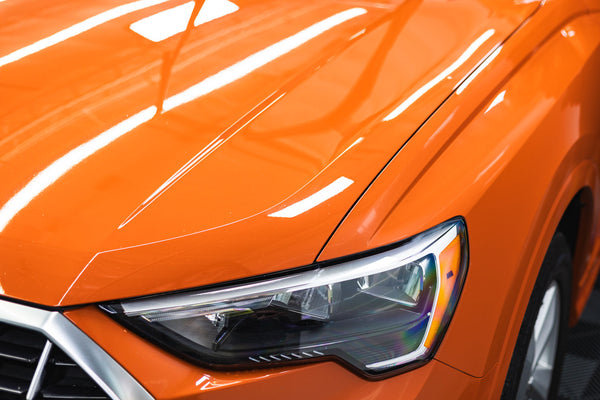 The headlight of an orange car.