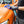 A person spraying Armour Detail Panel on an orange car and wiping it with a blue towel.