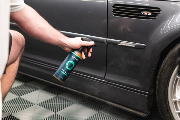 A closeup of a person spraying the side of their car with Armour Adapt.