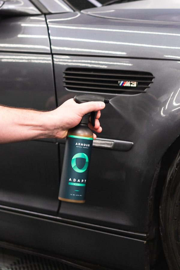 A closeup of a person spraying the side of their car with Armour Adapt.