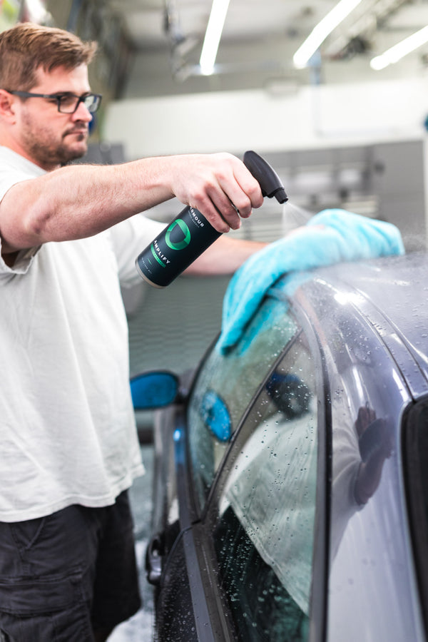 A person spraying the roof of a car with Armour Amplify and wiping it with a blue towel.