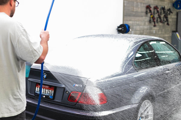 A person foaming a car with a foam cannon.