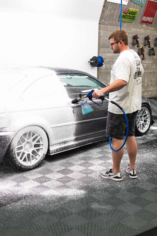 A person foaming a car with a foam cannon.