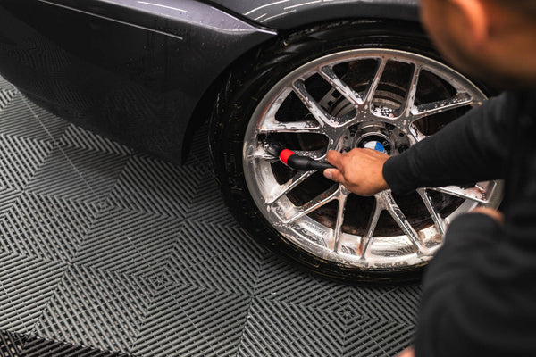 A closeup of a person cleaning a tire rim with a brush.