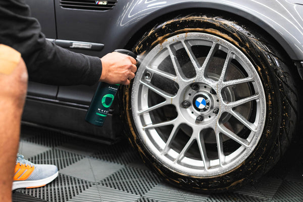 A person spraying Armour Wheel Cleaner on a dirty BMW tire.