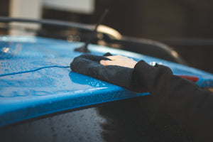 A and drying the roof of a car with a black towel.