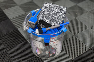 Detail Factory Clean Screen Avalanche placed on top of a clear wash bucket, holding detailing brushes and a microfiber wash mitt.