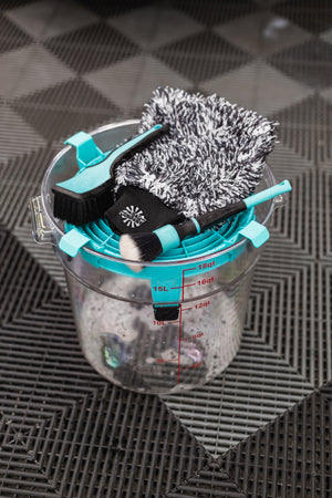 Detail Factory Clean Screen Riptide placed on top of a clear wash bucket, holding detailing brushes and a microfiber wash mitt.