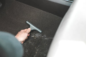 Detail Factory Pet Hair Rake used on the carpeted ground of a vehicle.