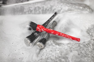 Three synthetic brushes piled on one another covered in foam.