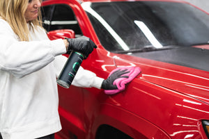Person applying Armour Detail Amplify to a red car with a pink microfiber towel.