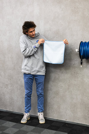 Person holding a white 16x16 dry me a river microfiber towel.