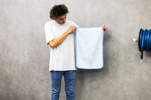 Person holding a light blue 16x24 dry me a river microfiber towel.