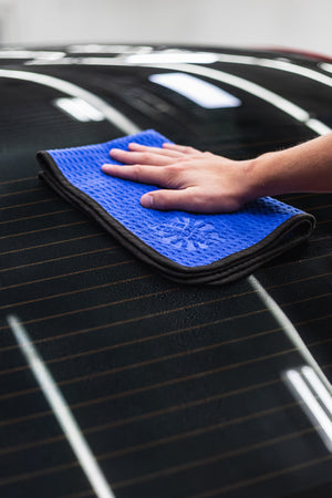 Person cleaning a car window with a navy blue 16x24 dry me a river microfiber towel.