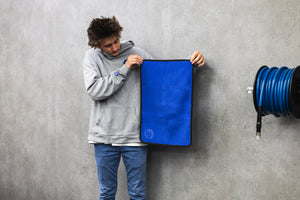 Person holding a navy blue 16x24 dry me a river microfiber towel.