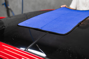 Person cleaning a car sunroof with a navy blue 20x40 dry me a river microfiber towel.