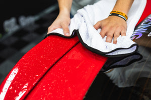 Person cleaning a car with a white 26x59 dry me a river microfiber towel.