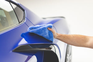 Using a blue Eagle Edgeless 500 towel from the Rag Company to detail the side and door of a blue Chevrolet C8 Corvette