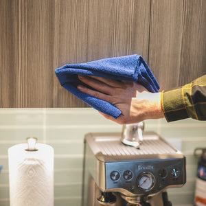 A person drying a cabinet door with a blue edgeless towel. 