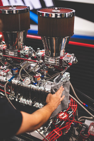 A person scrubbing an engine with a grey towel.