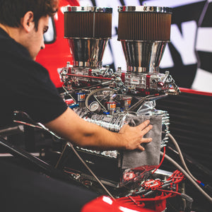 A person scrubbing an engine with a grey towel.