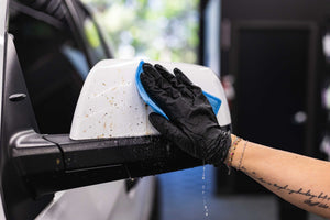 Gtechniq W8 Bug Remover being used with a Jersey Bug Scrubber on a white truck side mirror.