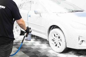 A person washing a car with an iK foam sprayer filled with KochChemie Active Foam.