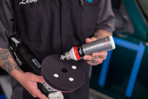 A person pouring KochChemie Heavy Cut onto a Heavy Cut Pad attached to a Rupes Polisher.
