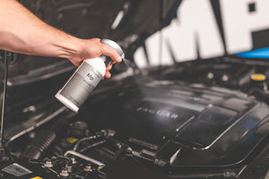 A person spraying Koch Chemie motorplast onto a cars engine.