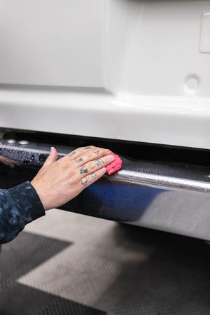 Person cleaning a car bumper with a KochChemie Abrasive Clay Bar.