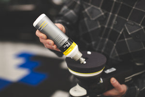 A person pouring fine cut liquid onto a KochChemie Fine Cut Pad attached to a Rupes Polisher.