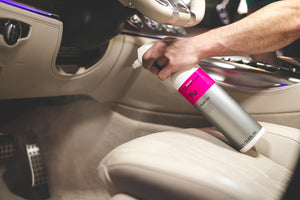 A person spraying the floor of the driver side of a car with Koch Chemie Fresh Up.