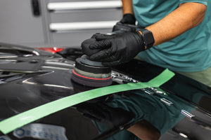 KochChemie Heavy Cut being used on a KochChemie Heavy Cut Pad v2 126mm attached to a polisher to show a before and after on the hood of a black car.