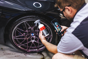 A person holding a spray bottle of Koch Chemie Magic Wheel Cleaner and taking a picture of it with their Iphone.