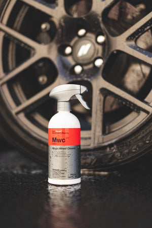 A spray bottle of Koch Chemie Magic Wheel Cleaner in front of a car tire.