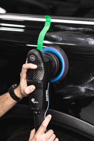 A person using a Rupes Polisher on a black vehicle.