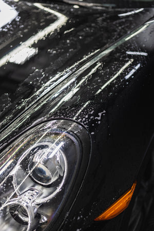 Close-up of a car's headlight with soapy residue.