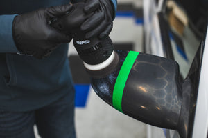 A person using a Rupes Polisher with a KochChemie One Cut and Finish Pad on a car side mirror.