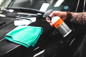 A person spraying KochChemie Panel Preparation Spray onto a green microfiber.
