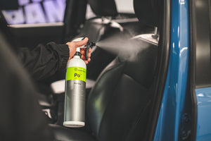 A person spraying a car seat with Koch Chemie Polstar.