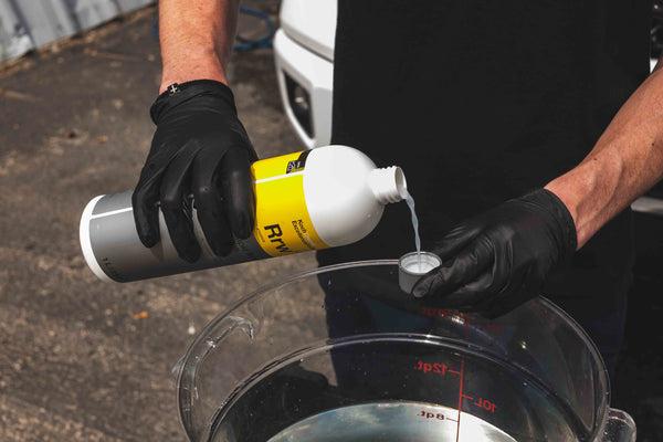 A person pouring Koch Chemie Rapid Rinseless Wash into it's bottle cap.