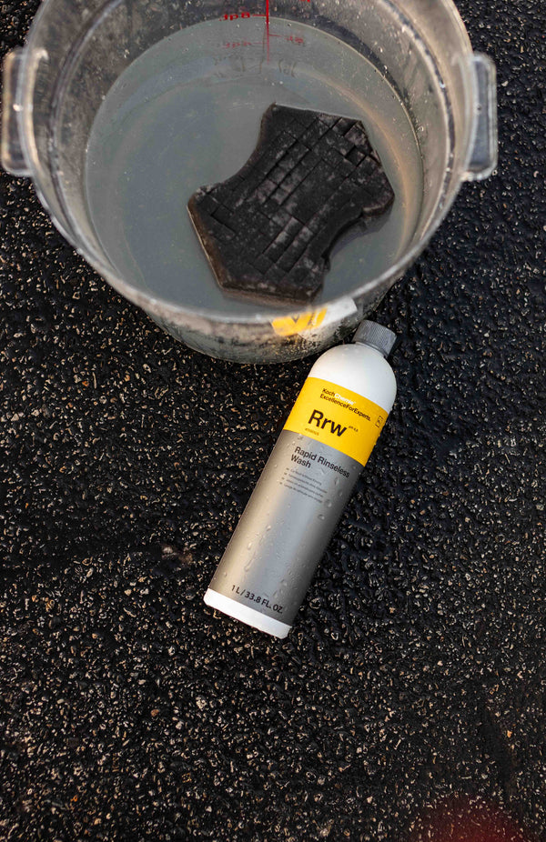 An Ultra Safe Sponge in a bucket with a bottle of Koch Chemie Rapid Rinseless Wash laying next to the bucket.