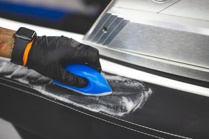 A person scrubbing upholstery with Leather and Vinyl Interior Cleaner. 